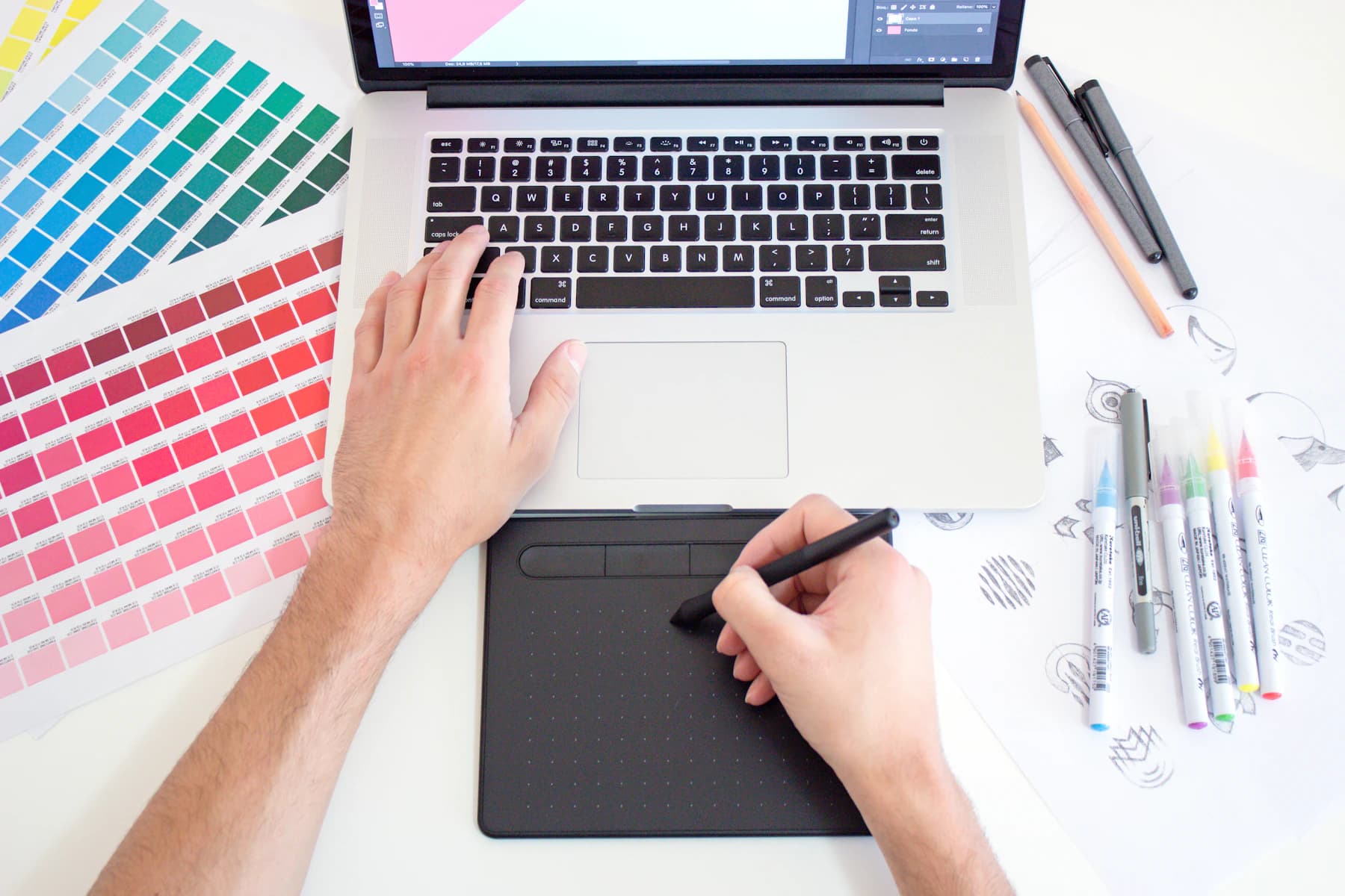 A graphic designer working with colour swatches and a drawing tablet.